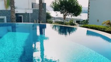 Yaz tatili olarak kristal mavi suyla yüzme havuzu ve havuz kenarında tropik cennet tatili.
