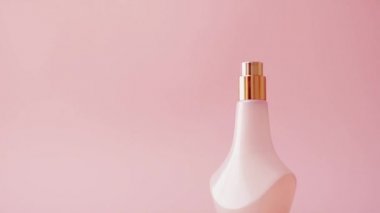 Pembe arka planda ürün promosyonu olarak taze çiçek kokulu parfüm şişesi.