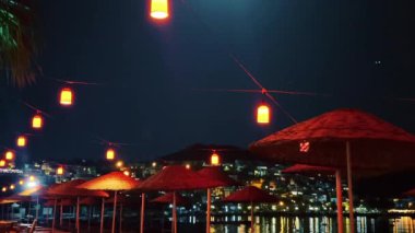 Plaj şemsiyeleri, fenerler ve yazlık otel tatil beldesinde palmiye ağaçları, açık hava dekorasyonu ve yaz tatili özgeçmişi.