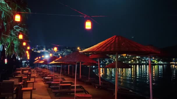 Sombrillas de playa, faroles y palmeras en el complejo hotelero junto al mar en la noche de verano, decoración al aire libre y vacaciones de verano b-roll — Vídeo de stock