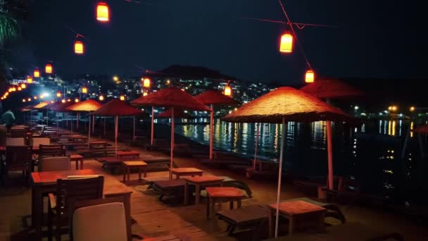 Strandparasols, lantaarns en palmbomen aan de kust hotel resort op zomernacht, outdoor decoratie en zomervakantie b-roll — Stockvideo