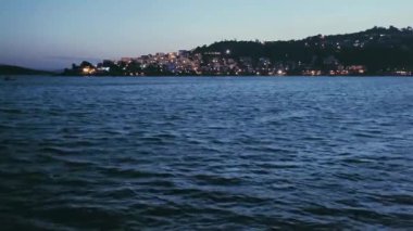 Deniz manzarası, seyahat ve doğa konsepti, deniz dalgaları ve kıyı kasabasının akşamları ışıkları