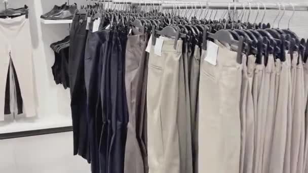 Concepto de moda, venta al por menor y compras, surtido de ropa elegante en perchas en la tienda de ropa de ropa — Vídeo de stock