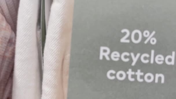 Concepto de moda y ropa sostenible. Etiqueta de algodón reciclado del 20 por ciento en la ropa en la tienda de la marca de ropa del mercado masivo en el centro comercial — Vídeo de stock