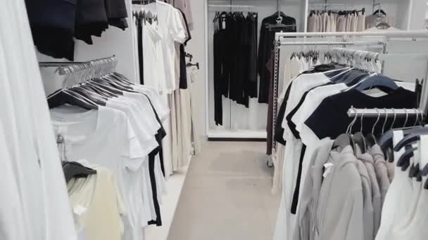 Концепция моды, розничной торговли и шоппинга, ассортимент стильной одежды на вешалках в магазине одежды — стоковое видео
