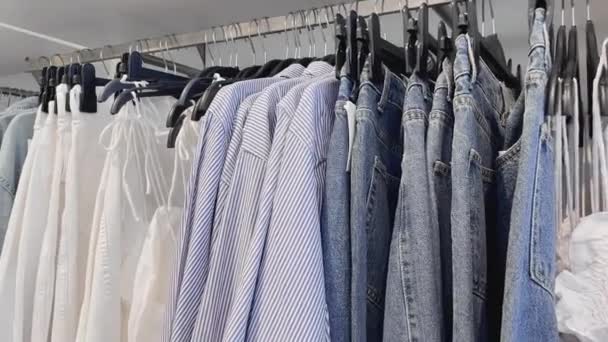 Divat, kiskereskedelmi és vásárlási koncepció, választéka elegáns ruhák vállfák ruházati bolt — Stock videók