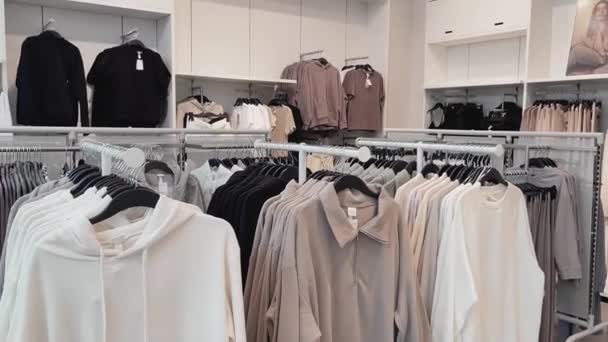 Concepto de moda, venta al por menor y compras, surtido de ropa elegante en perchas en la tienda de ropa de ropa — Vídeo de stock