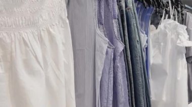 Moda, perakende ve alışveriş konsepti, giyim mağazasındaki askılarda çeşitli şık kıyafetler.