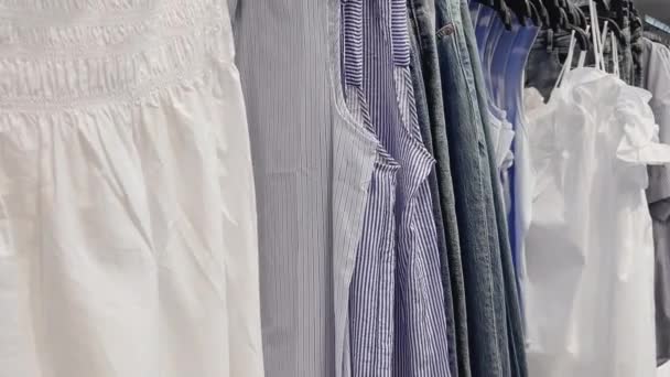Concepto de moda, venta al por menor y compras, surtido de ropa elegante en perchas en la tienda de ropa de ropa — Vídeo de stock