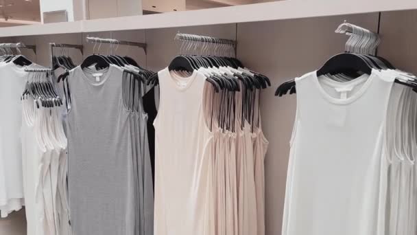 Fashion, retail en shopping concept, assortiment stijlvolle kleding op hangers in kledingwinkel — Stockvideo