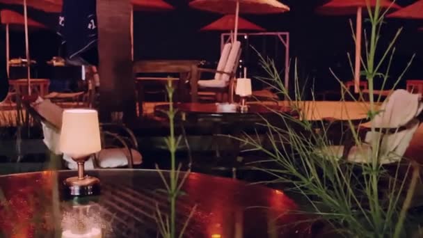 Data koncepcji projektowania wnętrz i nocy. Mała lampka vintage na stole w restauracji na świeżym powietrzu na plaży nad morzem — Wideo stockowe