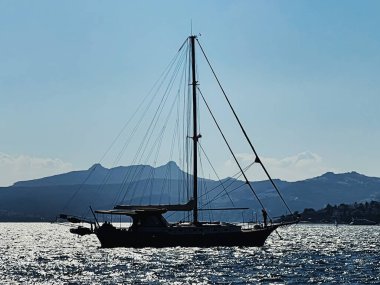 Sakin deniz manzarası ve kıyı doğası kavramı. Gün batımında deniz, kayıklar, dağlar ve mavi gökyüzü.