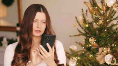 Noel telefon görüşmesi ve bayram tebrikleri. Noel gününde cep telefonu kullanan mutlu, gülümseyen kadın.