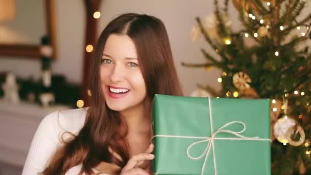 Vacanze di Natale e concetto di regalo sostenibile. Felice donna sorridente in possesso di regalo avvolto con carta da imballaggio verde eco-friendly — Video Stock