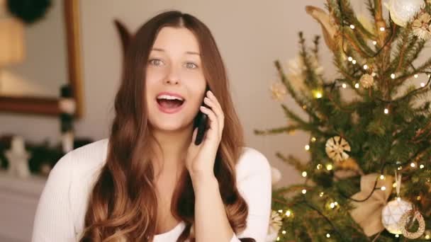 Kersttelefoongesprek en kerstgroet concept. Gelukkig glimlachende vrouw praten op mobiele smartphone op kerstdag — Stockvideo