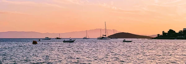 Концепция спокойного мыса и прибрежной природы. Море, лодки, горы и голубое небо над горизонтом на восходе солнца — стоковое фото
