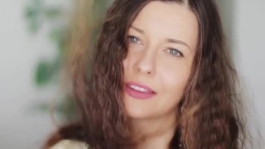 Uzun, sağlıklı kıvırcık saçlı, esmer, dalgalı, kıvırcık saçlı mükemmel beyaz dişli gülüşlü, güzel yüzlü ve doğal organik saç bakım reklamı olan güzel bir kadın.