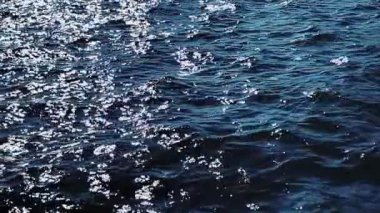 Mavi okyanus suyunun yüzey arka planı olarak yavaş hareket etmesi, dalgalı dalgalar ve yaz tatili seyahatleri deniz, doku ve kıyı doğası kavramı olarak devam ediyor.