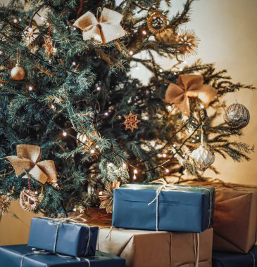Noel teslimatı ve sürdürülebilir hediye konsepti. Donanma mavisi hediye kutuları geri dönüşümlü kağıtlarla süslenmiş Xmas ağacının altına sarılmış çevre dostu ambalajlar.