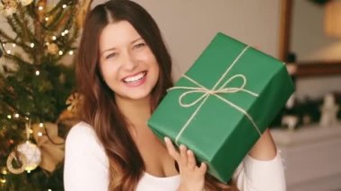 Noel tatili ve çevre dostu hediye konsepti. Elinde sürdürülebilir ambalaj kağıdına sarılı yeşil hediye paketi tutan mutlu bir kadın.