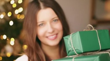 Noel tatili ve çevre dostu hediye konsepti. Elinde sürdürülebilir yeşil ambalaj kağıdına sarılı hediye kutuları tutan mutlu bir kadın.