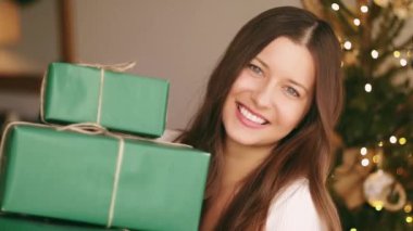 Noel tatili ve çevre dostu hediye konsepti. Elinde sürdürülebilir yeşil ambalaj kağıdına sarılı hediye kutuları tutan mutlu bir kadın.