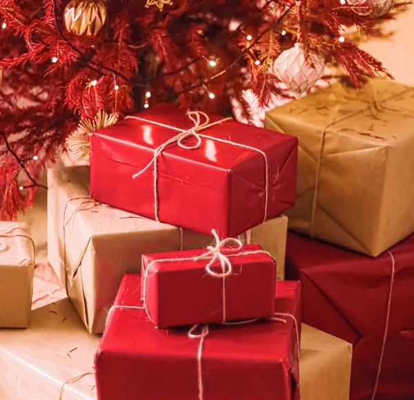 Entrega navideña y concepto de regalos sostenibles. Cajas de regalo rojas envueltas en un embalaje ecológico con papel reciclado bajo un árbol de Navidad decorado —  Fotos de Stock