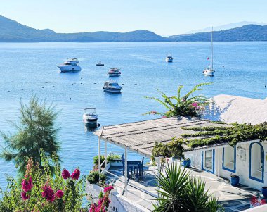 Yaz tatili ve deniz kenarı cennet konsepti. Deniz kenarındaki beyaz geleneksel villa, yazları yatlar ve dağlar.