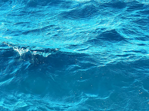 Zee, textuur en kust natuur concept. Blauwe oceaan water als achtergrond, vloeiende golven en zomervakantie reizen — Stockfoto