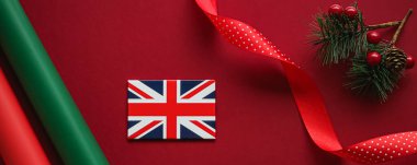 İngiliz Noel geleneği ve tatil tasarımı konsepti. Büyük Britanya 'nın İngiliz bayrağı ve kırmızı zemin üzerindeki xmas süslemeleri ve dekorasyonu düz üst görünüm olarak gösteriyor