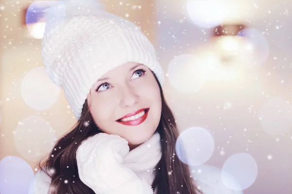 Natal, pessoas e conceito de férias de inverno. Feliz sorrindo mulher vestindo chapéu de malha branco como close-up xmas rosto retrato, brilho de neve e efeito bokeh — Fotografia de Stock