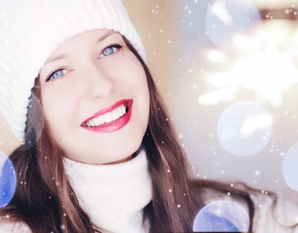 Jul, människor och vintersemester koncept. Glad leende kvinna bär vit stickad hatt som närbild ansikte xmas porträtt, snö glitter och bokeh effekt — Stockfoto