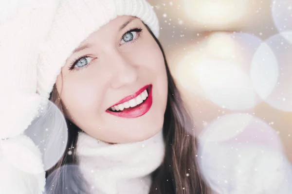 Natal, pessoas e conceito de férias de inverno. Feliz sorrindo mulher vestindo chapéu de malha branco como close-up xmas rosto retrato, brilho de neve e efeito bokeh — Fotografia de Stock