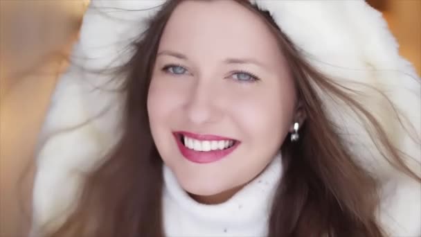 Wintermode und Weihnachts-Look. Schöne lächelnde Frau in weißem Pullover und flauschigem Pelzmantel mit Kapuzenmantel als Weihnachtsporträt — Stockvideo