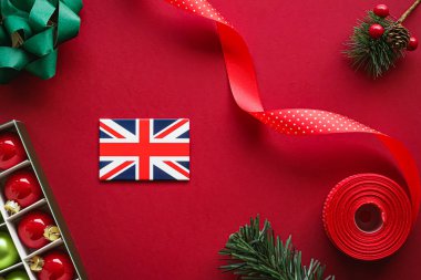 İngiliz Noel geleneği ve tatil tasarımı konsepti. Büyük Britanya 'nın İngiliz bayrağı ve kırmızı zemin üzerindeki xmas süslemeleri ve dekorasyonu düz üst görünüm olarak gösteriyor