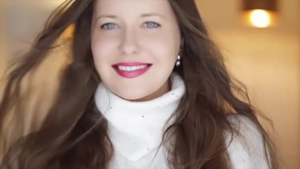 Zimní krása a vánoční svátky vzhled. Krásná usmívající se žena v bílém pleteném svetru, přírodní make-up a dlouhý účes s rozcuchanými vlasy — Stock video