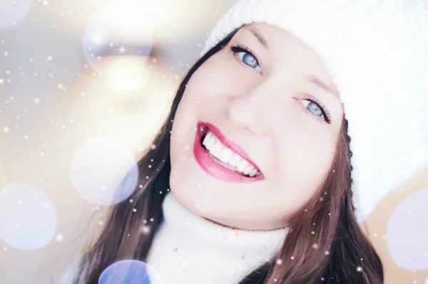 Christmas, people and winter holiday concept. Happy smiling woman wearing white knitted hat as closeup face xmas portrait, snow glitter and bokeh effect — Stock Photo, Image