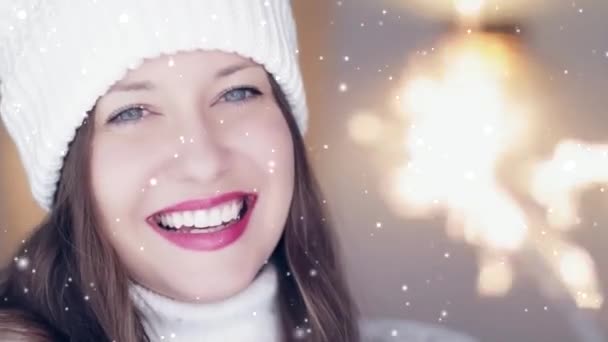 Konsep liburan musim dingin dan perayaan Natal. Happy tersenyum wanita di musim dingin putih rajutan topi dan sweater memegang kembang api terbakar, salju turun dan kepingan salju — Stok Video