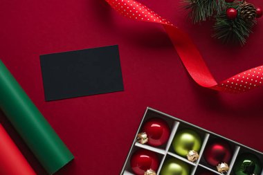 Bayram marka kimlik tasarımı ve Noel yassı yatak konsepti. Siyah boş kartvizit ve xmas süsü ve kırmızı kağıdın arka planındaki süsleme düz olarak yatar.