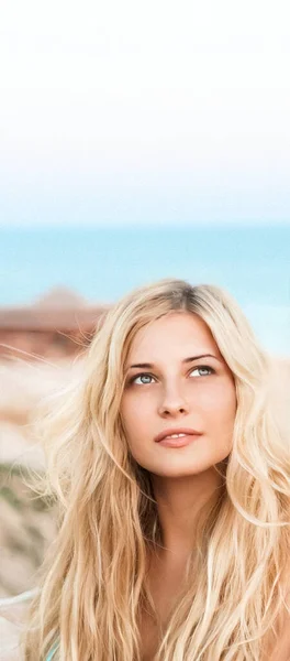 Ομορφιά, ευεξία και καλοκαιρινό πορτρέτο. Όμορφη νεαρή γυναίκα με μακριά ξανθά μαλλιά, χαρούμενη ξανθιά χαμογελαστή, μπλε θάλασσα στο φόντο — Φωτογραφία Αρχείου
