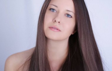 Güzellik, saç stili ve doğal makyaj. Uzun düz saçlı güzel bir kadın, kusursuz bir cilt ve organik kozmetik makyaj, yumuşak odaklı bir portre ve geçmişe dönük film tahıl etkisi