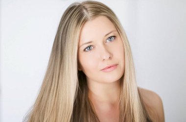 Güzellik, saç stili ve doğal makyaj. Uzun sarı düz saçlı güzel bir kadın, kusursuz bir cilt ve organik kozmetik makyaj, yumuşak odaklı bir portre ve geçmişe dönük film tahıl etkisi.