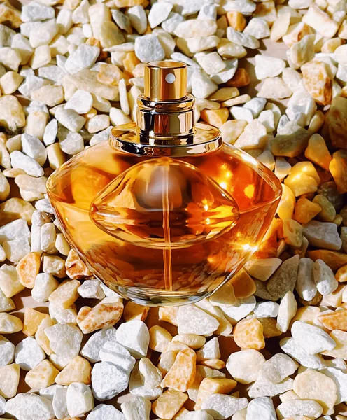 Parfüm şişesi, lüks koku, taş arka planda cam şişe, güzellik ürünü konsepti.
