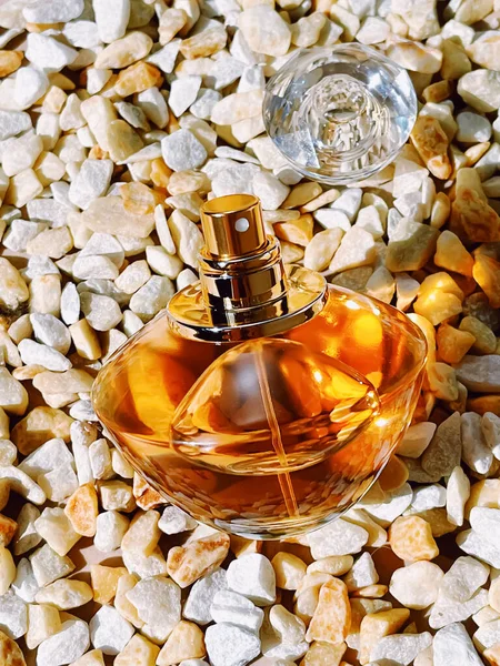 Parfüm şişesi, lüks koku, taş arka planda cam şişe, güzellik ürünü konsepti.