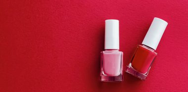 Kırmızı arka planda kırmızı ve pembe oje şişeleri, manikür ve güzellik kozmetik konsepti