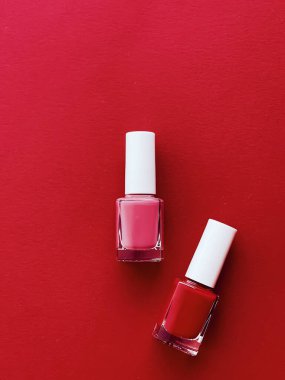 Kırmızı arka planda kırmızı ve pembe oje şişeleri, manikür ve güzellik kozmetik konsepti