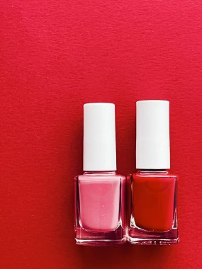 Kırmızı arka planda kırmızı ve pembe oje şişeleri, manikür ve güzellik kozmetik konsepti
