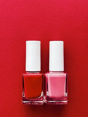 Kırmızı arka planda kırmızı ve pembe oje şişeleri, manikür ve güzellik kozmetik konsepti