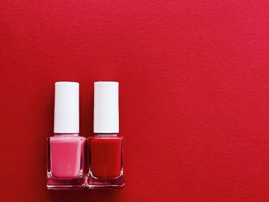 Kırmızı arka planda kırmızı ve pembe oje şişeleri, manikür ve güzellik kozmetik konsepti
