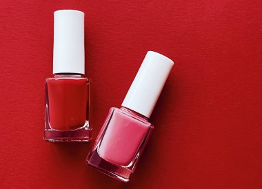 Kırmızı arka planda kırmızı ve pembe oje şişeleri, manikür ve güzellik kozmetik konsepti